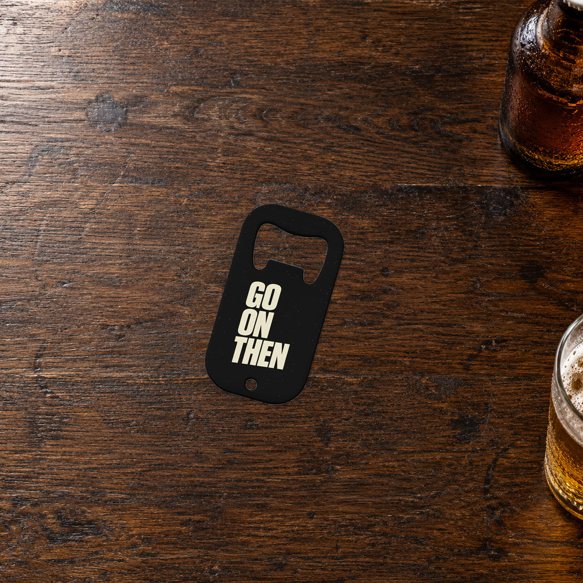 GO ON THEN bottle opener on a bar, showing the exact cream-on-black printed front